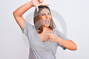 Portrait of beautiful young woman standing over isolated white background smiling making frame with hands and fingers with happy