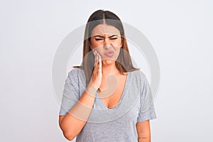 Portrait of beautiful young woman standing over isolated white background touching mouth with hand with painful expression because