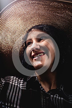 Portrait of a beautiful young woman in a straw hat with a creative shadow pattern on the face