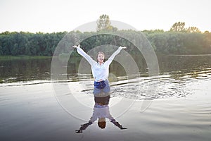 Portrait of a beautiful young woman in stylish dress with white shirt and jeans in water of river or lake in nature