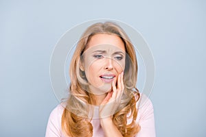 Portrait of beautiful, young, woman suffering from terrible strong teeth pain, touching cheek with hand over grey background, too