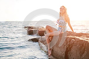 Portrait of beautiful young woman in sunglasses and bikini on beach. Female model posing in swimsuit on sea shore