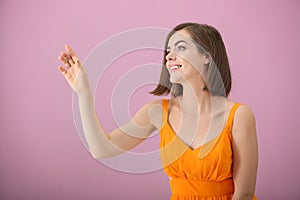 Portrait of beautiful young woman touching something on color background