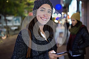 Portrait of beautiful young woman using her mobile phone at nigh