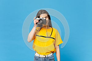 Portrait of beautiful young woman in vivid casual clothes take pictures on retro vintage photo camera isolated on bright