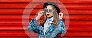 Portrait beautiful young woman wearing a black round hat, blue knitted coat on red background