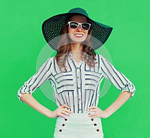 Portrait beautiful young woman wearing a black round summer hat, white striped shirt on green background