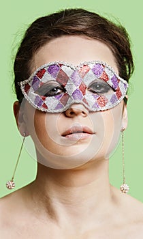 Portrait of beautiful young woman wearing eye mask against green background