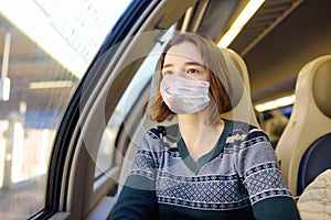 Portrait of a beautiful young woman wearing face mask in a train car. Countries reopening borders from lockdown. Social distancing