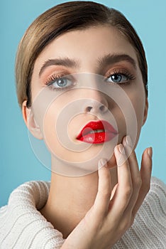 Portrait of beautiful young woman wearing red clothes with perfect young skin, red matt lips and nails