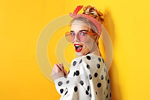 Portrait of beautiful young woman wearing sunglasses on color background