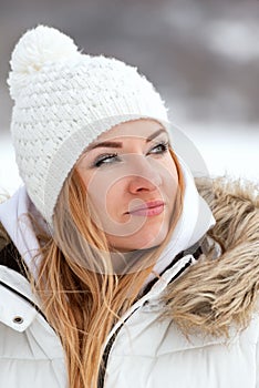 Portrait of beautiful young woman in white knitted hat with red-haire outdoors. Winter portrait. Vertical frame