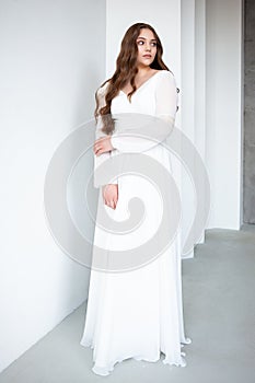 portrait of beautiful young woman in white wedding dress posing in studio.