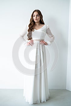 portrait of beautiful young woman in white wedding dress posing in studio.