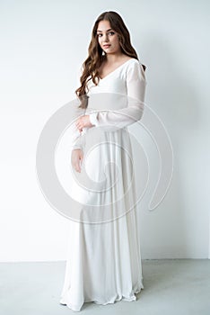 portrait of beautiful young woman in white wedding dress posing in studio.