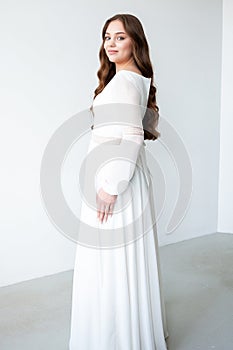 portrait of beautiful young woman in white wedding dress posing in studio.