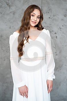 portrait of beautiful young woman in white wedding dress posing in studio.