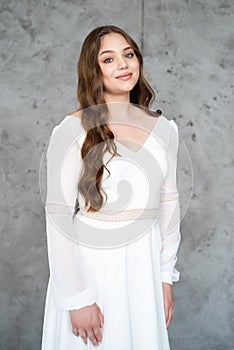 portrait of beautiful young woman in white wedding dress posing in studio.