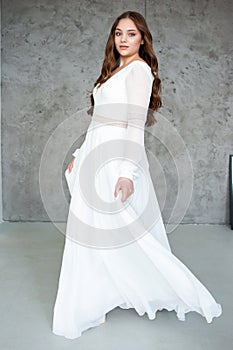 portrait of beautiful young woman in white wedding dress posing in studio.