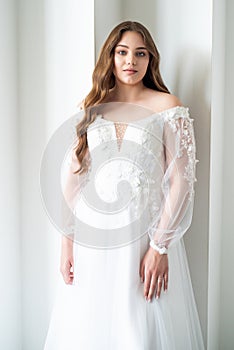 portrait of beautiful young woman in white wedding dress posing in studio.