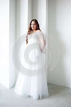 portrait of beautiful young woman in white wedding dress posing in studio.