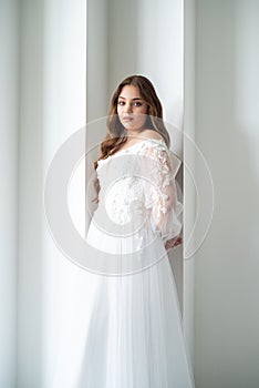 portrait of beautiful young woman in white wedding dress posing in studio.