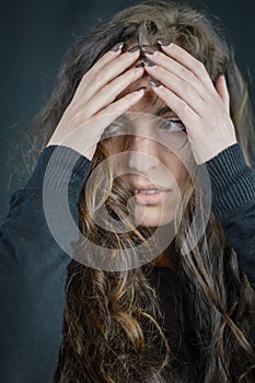 Portrait of a beautiful young woman who tries to hide her face with her hands and go unnoticed