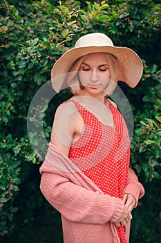 Portrait of beautiful young woman in wide beach hat, against background of summer green park