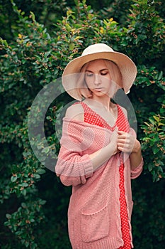 Portrait of beautiful young woman in wide beach hat, against background of summer green park