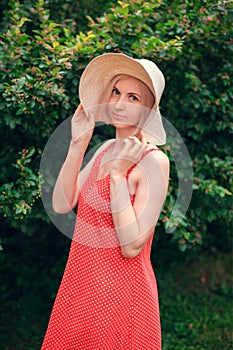 Portrait of beautiful young woman in wide beach hat, against background of summer green park