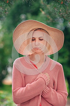 Portrait of beautiful young woman in wide beach hat, against background of summer green park