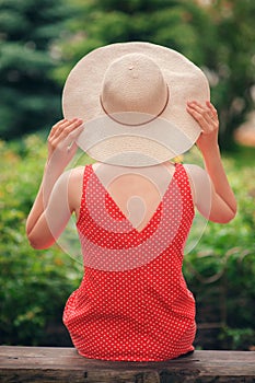 Portrait of beautiful young woman in wide beach hat, against background of summer green park