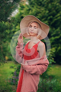 Portrait of beautiful young woman in wide beach hat, against background of summer green park