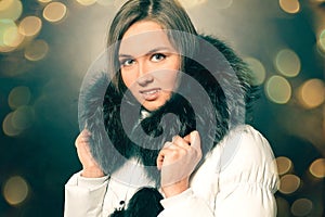 portrait of beautiful young woman in winter jacket. Beautiful bokeh effect from a garland.