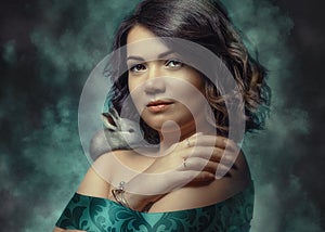 Portrait of a beautiful young woman wrapped in ribbon and a small rabbit on her shoulder