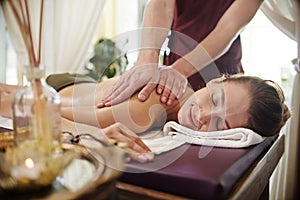 Smiling Young Woman Enjoying Massage in SPA