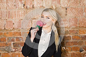 Portrait of beauty business woman with lolipop and santa hat wearing. Brick red background.