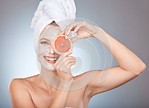 Portrait, beauty and facial with a woman in studio on a gray background holding an orange slice for natural care. Face