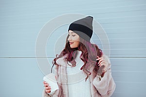 Portrait of beauty fashion smiling woman with coffee in mink coat and black hat on pink background. Outdoor