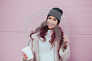 Portrait of beauty fashion smiling woman with coffee in mink coat and black hat on pink background. Outdoor