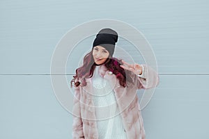 Portrait of beauty fashion smiling woman with colored ombre hairstyle, making peace by fingers in mink coat on grey