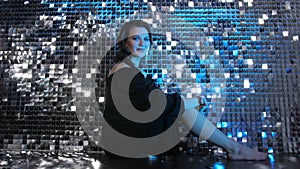 Portrait of beauty fashion smiling young woman sitting on floor in neon light