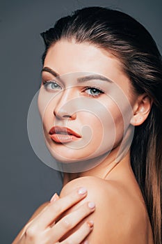 Portrait of beauty girl with beauty skin, touch body with hands on grey background. Cosmetics or spa, healtcare concept.