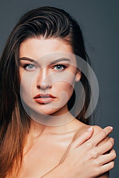 Portrait of beauty girl with beauty skin, touch body with hands on grey background. Cosmetics or spa, healtcare concept.