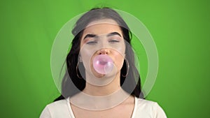 Portrait of beauty girl blowing big bubble gum on green screen