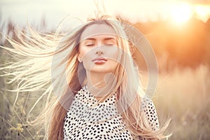 Portrait of beauty girl with fluttering white hair enjoying nature outdoors. Flying blonde hair on the wind. Beautiful young woman