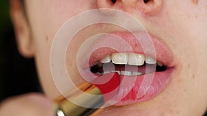 Portrait of beauty girl who ineptly paints lips with bright red lipstick. Macro shot of young woman make up lips applying red lips