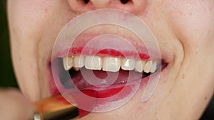 Portrait of beauty girl who ineptly paints lips with bright red lipstick. Macro shot of young woman make up lips applying red lips