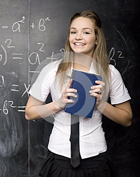 Portrait of beauty happy student with books near blackboard