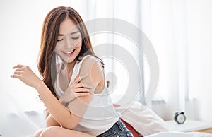 Portrait of beauty  smiling asian woman applying a lotion to her arm skin during her morning routine.